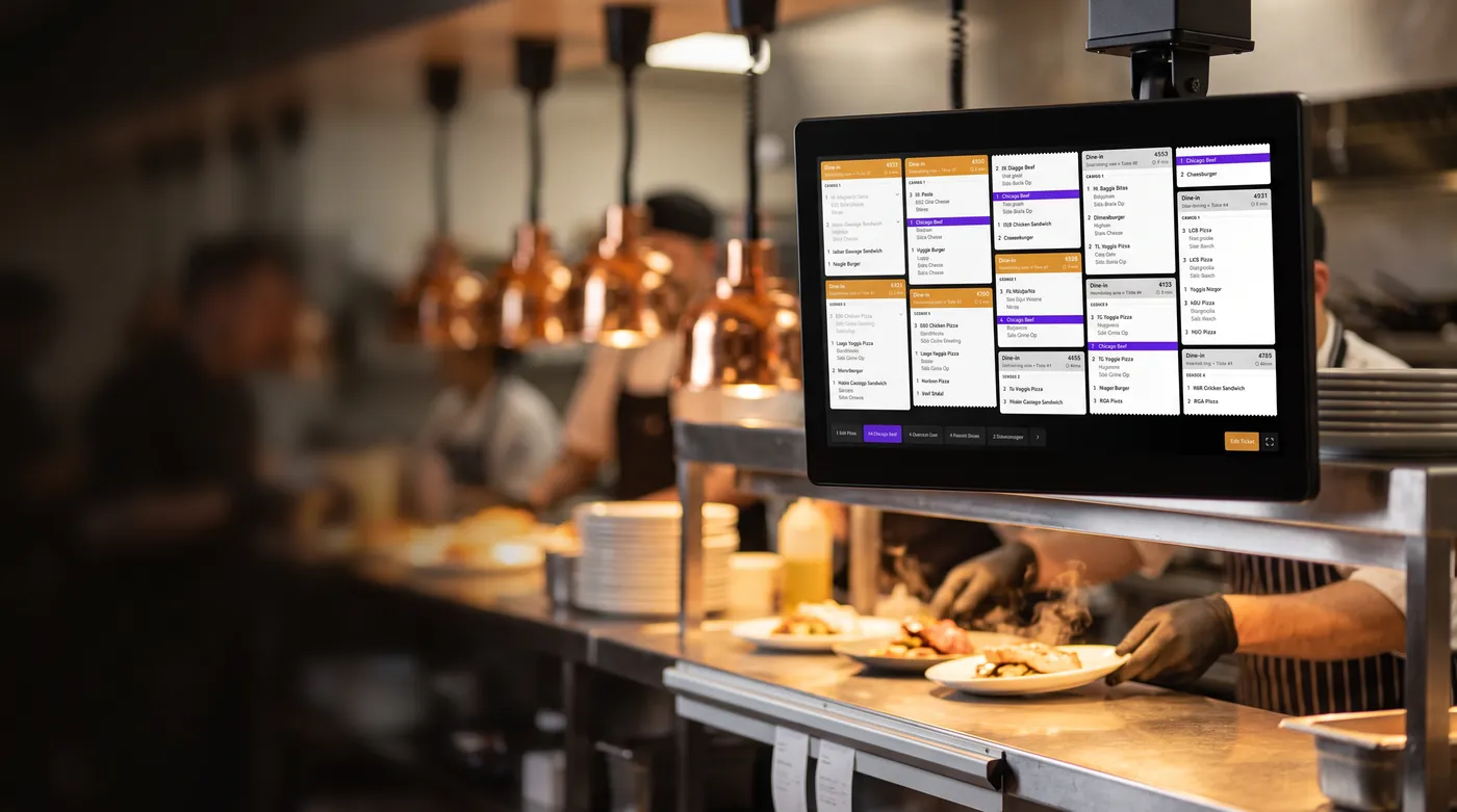 Tabski kitchen display system mounted above a restaurant kitchen pass under heat lamps