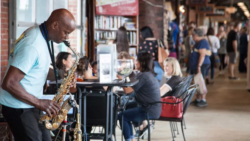 A saxophone player performing inside the 2nd Street Market in Dayton as shoppers browse vendor stalls
